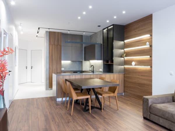 Modern open-plan kitchen and dining area with wood, gray cabinets, and track lighting.